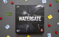 Watergate board game box by Matthias Cramer, featuring a dark cracked-glass design with the Capstone Games logo, surrounded by scattered game components.