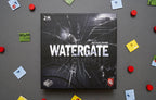 Watergate board game box by Matthias Cramer, featuring a dark cracked-glass design with the Capstone Games logo, surrounded by scattered game components.