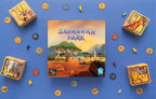 Savannah Park board game box front featuring illustrated African wildlife including giraffe, oryx, and meerkat, surrounded by colorful game components on a blue background.