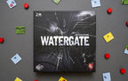 Watergate board game box by Matthias Cramer, featuring a dark cracked-glass design with the Capstone Games logo, surrounded by scattered game components.