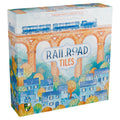 Railroad Tiles board game box featuring a watercolor illustration of a blue steam train crossing a brick viaduct above a colorful village.