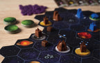Close-up of Gaia Project's hex-tile space board showing brown and blue faction buildings on planet tokens with green and purple pieces nearby.