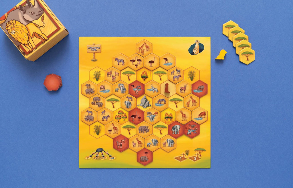 Savannah Park board game laid out showing the hexagonal tile game board with safari animals, plus the game box, wooden meeple, and acacia tree hexagon tiles.
