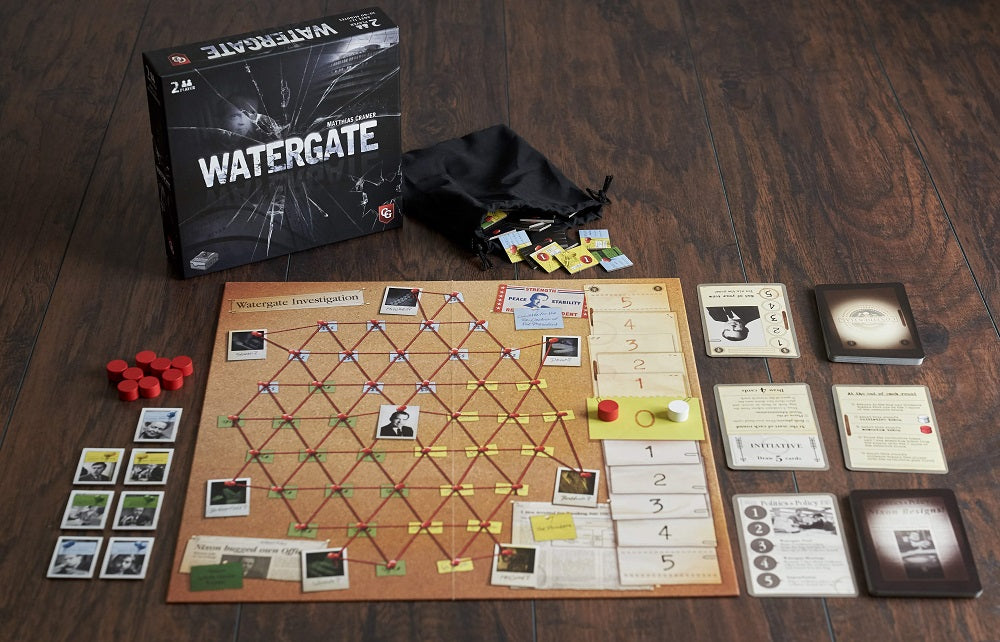 Watergate board game components spread on a wooden table including cork investigation board, cards, tokens, dice, and game box.