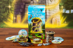 Wandering Towers: The Magic Tower expansion box surrounded by game components including tower miniatures, round tiles, meeples, and token pieces on a wooden table.