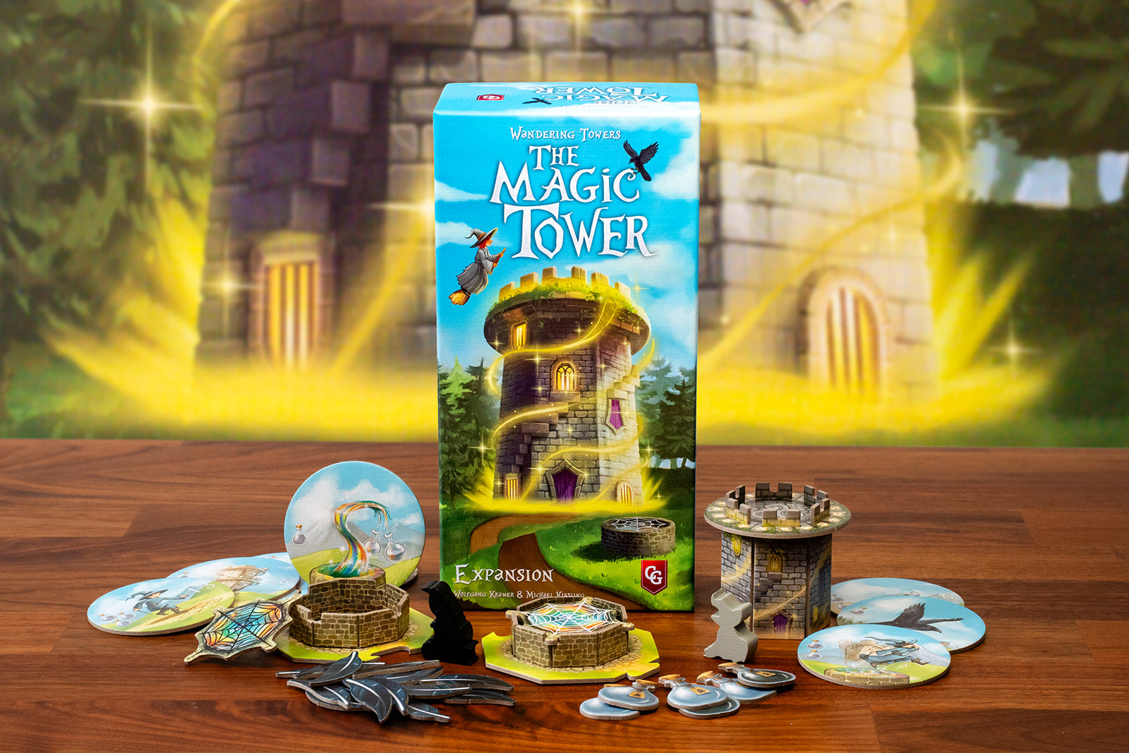 Wandering Towers: The Magic Tower expansion box surrounded by game components including tower miniatures, round tiles, meeples, and token pieces on a wooden table.