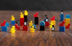 Colorful wooden animal meeples and cubes from Ark Nova Marine Worlds including cats, penguins, and fish in red, blue, yellow, and black.