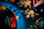Close-up of SETI board game in play, showing colorful meeples and discs on a solar system board near Saturn and Europa.