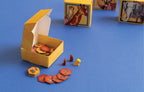 Savannah Park board game components including animal-illustrated hexagonal tiles, wooden meeples, and large animal-art dice on a blue surface.