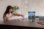 Smiling young woman reaching across a dark table to play Vantage board game, with game box, cards, tokens, and dice visible.