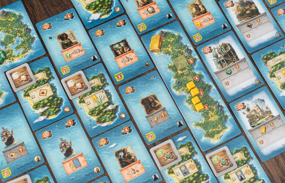 Pirates of Maracaibo game cards spread on a wooden table, including island tiles, character cards, and yellow gold cube tokens.