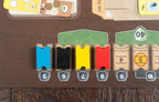 Close-up of Ark Nova Marine Worlds board showing colored wooden ticket tokens in blue, black, yellow, and red slotted into numbered card holders on a game board.